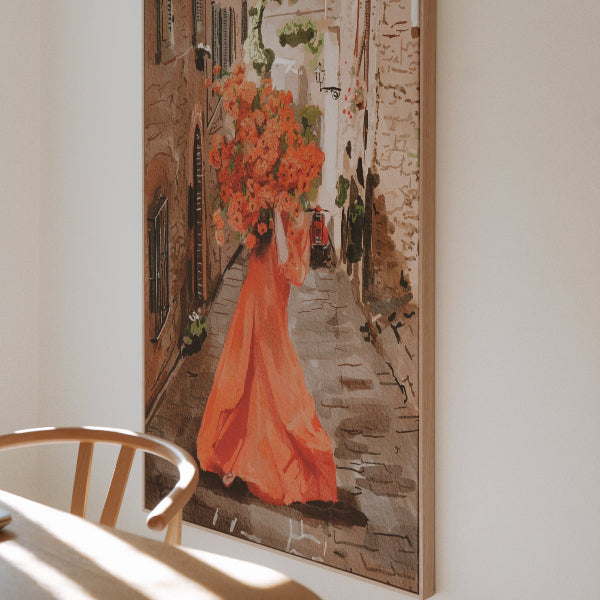Painting of a woman in an orange dress holding flowers on a wall in a room with a table and chair.