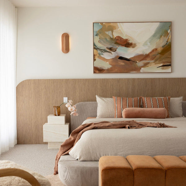 Modern bedroom with abstract painting, bed, and side table.