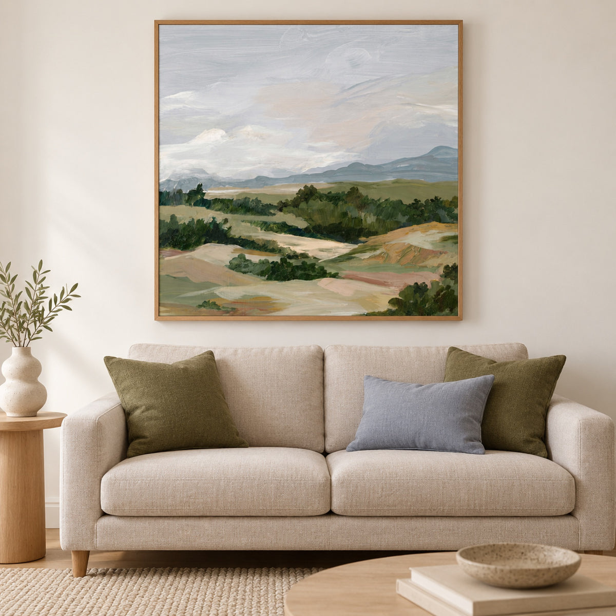 Gentle Hills Under Cloudy Skies displayed in an oak frame above a pale linen sofa.