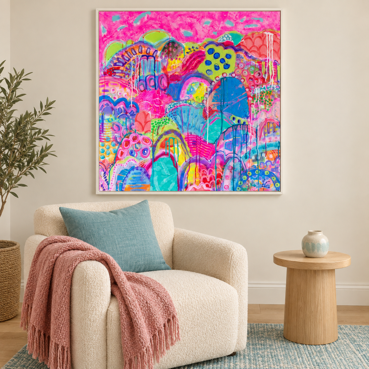 The Joy Parade by Lindy Farley in a white frame above a cream armchair with aqua and rose textiles.
