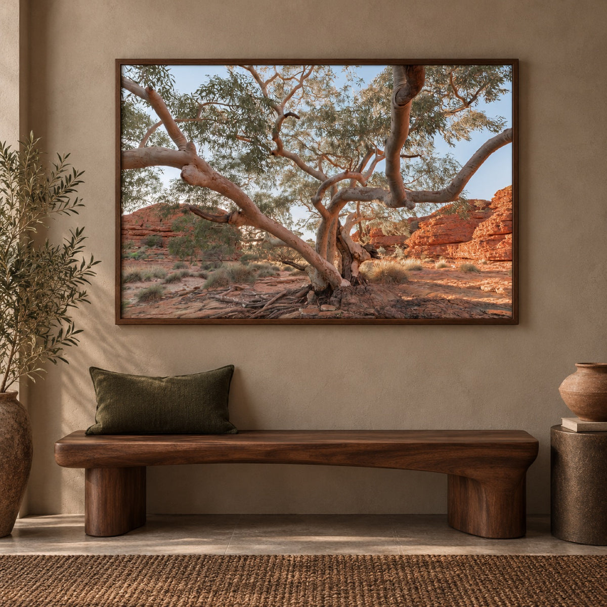Twisting Gum Tree in a walnut frame above a dark timber bench with an olive cushion and terracotta ceramics.