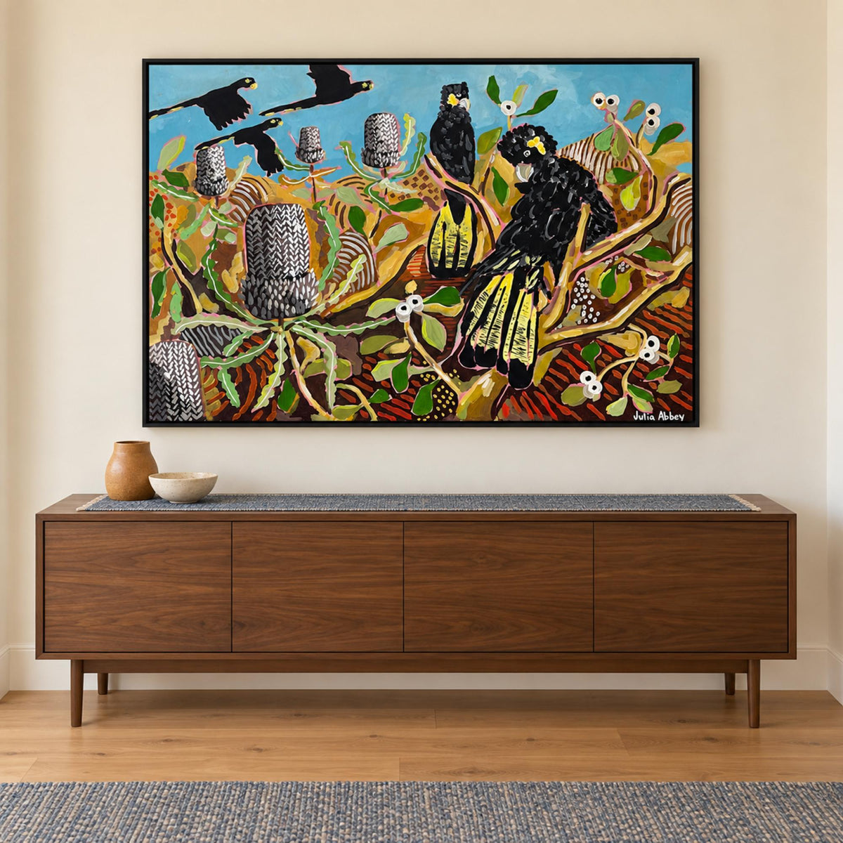 Basking In Banksias in a black frame above a walnut console with ochre and ivory ceramics.