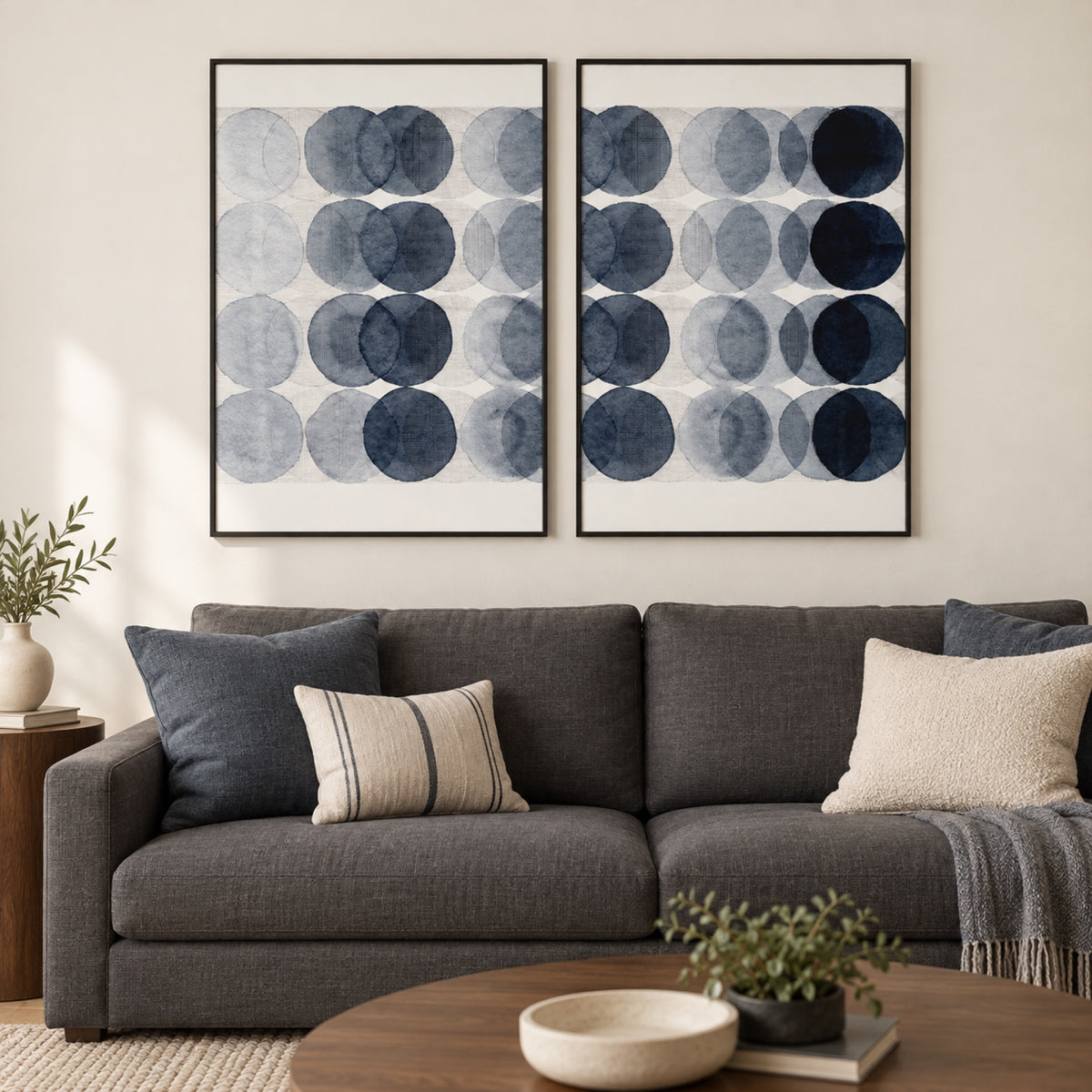 Overlapping, Style A and B, Set Of 2 in slim black frames above a charcoal sofa with blue-grey and cream cushions.