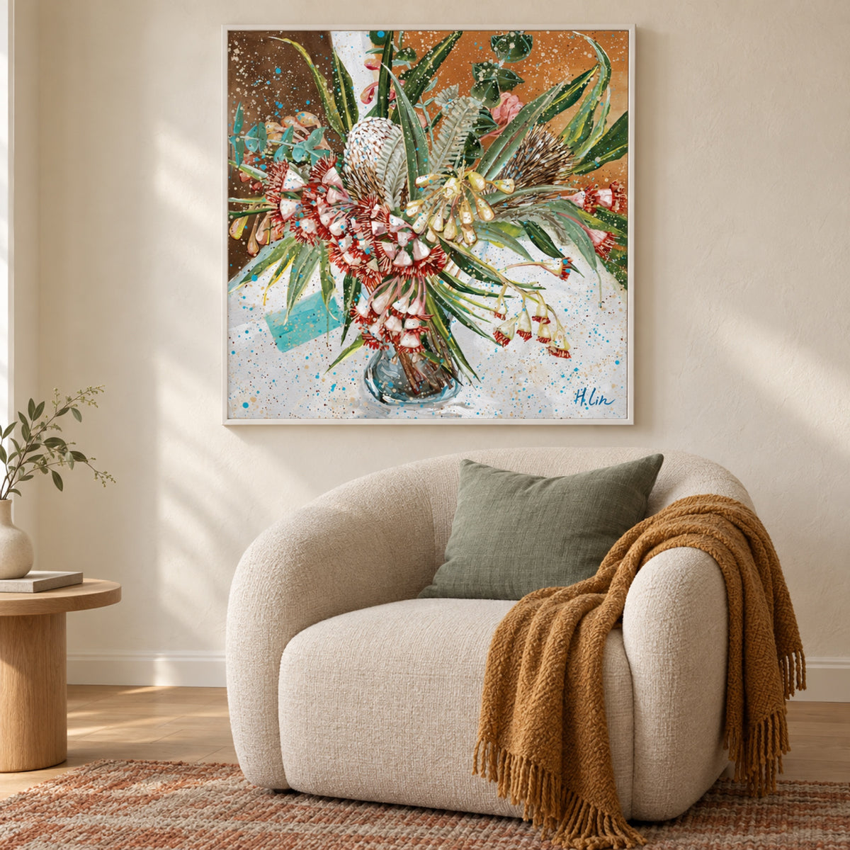 Glowing Radiance by Hsin Lin in a slim white frame above a cream armchair, styled with a eucalyptus green cushion, ochre throw and terracotta rug.