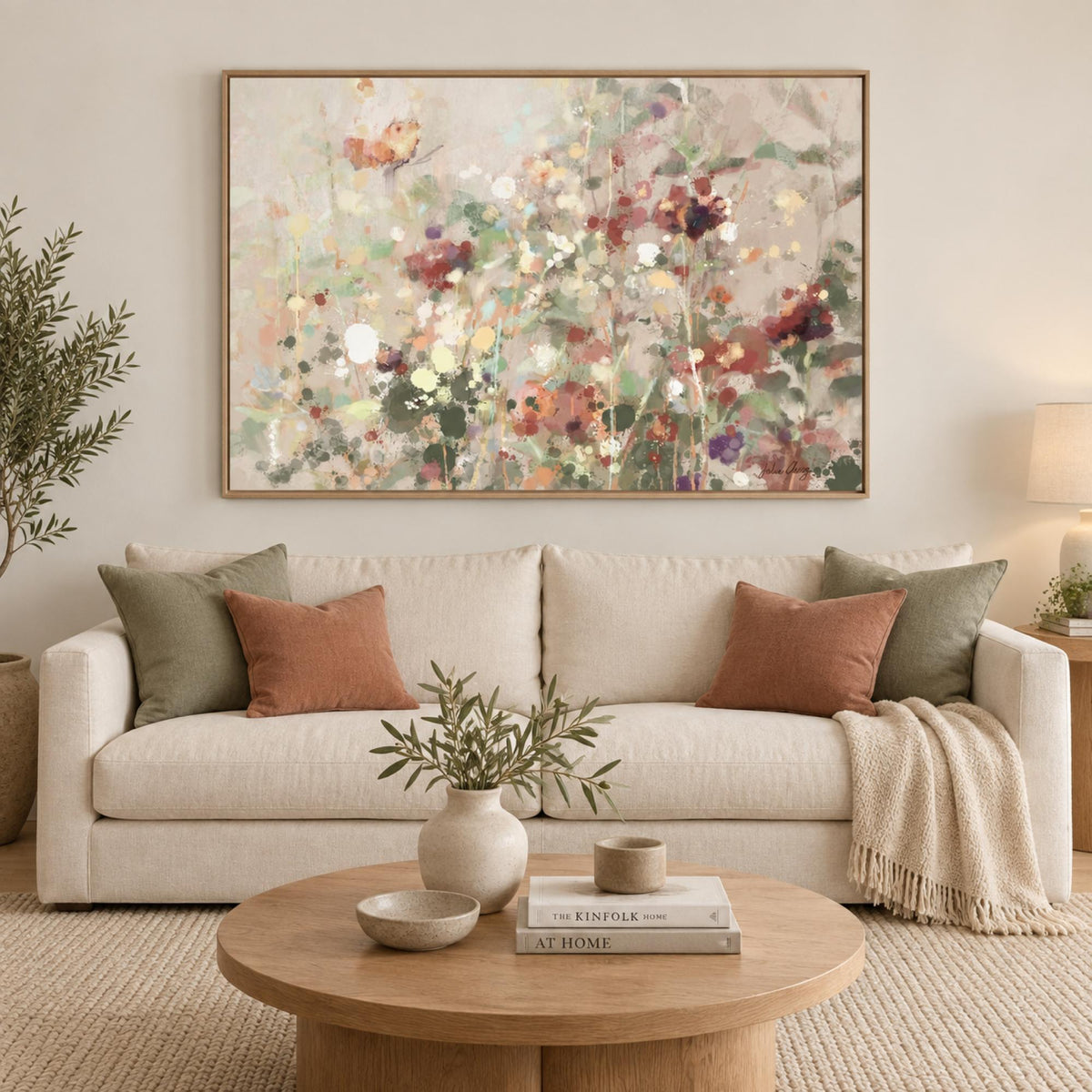 Painted Wildflower Meadow in an oak frame above a cream sofa with sage and terracotta cushions.