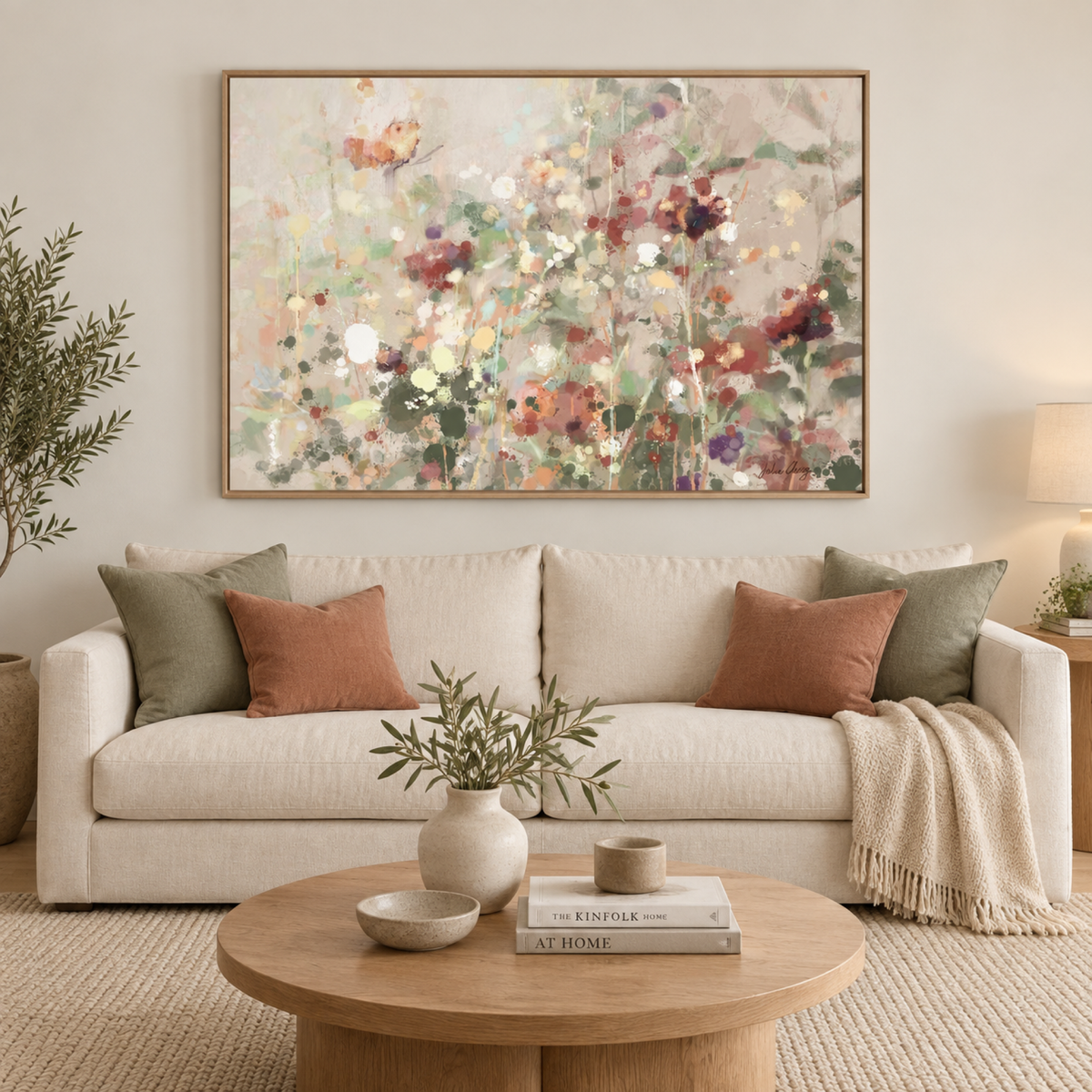 Painted Wildflower Meadow in an oak frame above a cream sofa with sage and terracotta cushions.