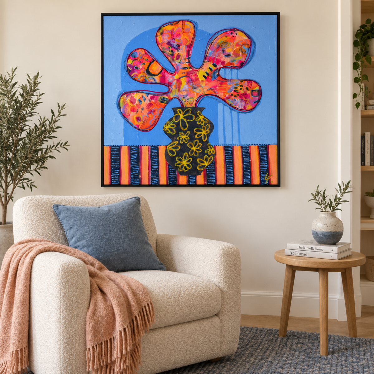 Sybil by Lindy Farley in a black frame above a cream chair with blue and peach textiles.